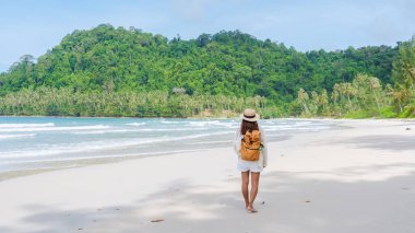 Sırt çantalı Asyalı kadın Koh Kood Adası 'nda yürüyor. Tayland Trat, tropik ada Ko Kut Adası sahilinde yürüyen gezgin. 