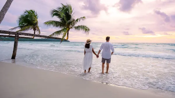 美しいハンギングヤシの木 ヤシの木とトロピカルビーチとクック島コッド島のビーチで日没を見ている男性と女性のカップル — ストック写真