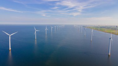 Bulutları ve mavi gökyüzü olan bir yel değirmeni parkının yukarıdan görünüşü, okyanus havası manzaralı rüzgar türbini Flevoland Hollanda Ijsselmeer ile birlikte. Hollanda 'da Yeşil Enerji Üretimi
