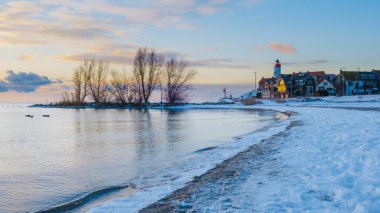 Hollanda Deniz Feneri kışın Hollanda 'da akşamları plajda gün batımında kar yağar.