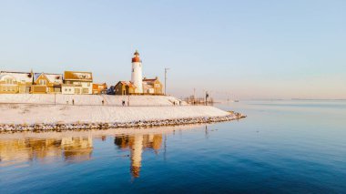 Hollanda deniz feneri kışın Hollanda 'da kar yağarken okyanusta yansımalar görülür.