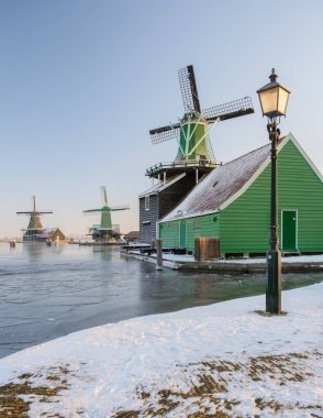 Zaanse Schans Hollanda günbatımında Hollanda 'da bir yel değirmeni köyü. Hollanda' da kış boyunca karlı bir köy.