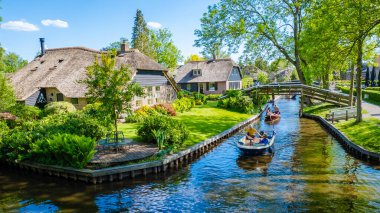 Giethoorn Hollanda 9 Mayıs 2020 'de, Avrupa' da sıcak bir bahar günü, kanalları ve kırsal sazdan çatı evleriyle ünlü köyü teknelerle ziyaret eden turistler görülüyor.