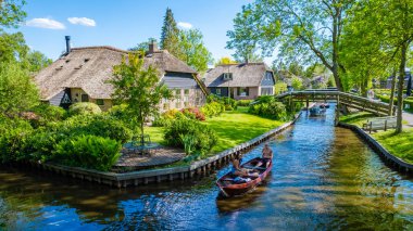 Giethoorn Hollanda 9 Mayıs 2020 'de, Avrupa' da sıcak bir bahar günü, kanalları ve kırsal sazdan çatı evleriyle ünlü köyü teknelerle ziyaret eden turistler görülüyor.