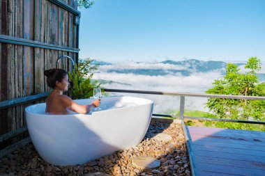 Tatil sırasında Chiang Rai Kuzey Tayland dağlarına bakan Asyalı kadınlar. Dışarıda banyo, gün batımında küvet.