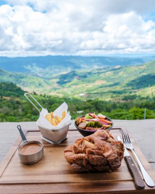 Tatil sırasında Chiang Rai Kuzey Tayland dağlarına bakan Alman domuz budu. Dağlarda bir restoranda Alman domuz budu.