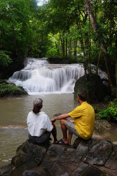 Deep forest waterfall in Thailand. Erawan Waterfall in National Park. a couple of men and women relaxing in the jungle forest on a trip visiting nature with forest and waterfalls