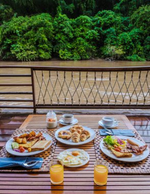 Tayland 'da Kwai nehri kıyısındaki tropikal bir sahil evinde kahvaltı masası. Kwai Kanchanaburi nehrinde yüzen ahşap bir sal evi, Tayland