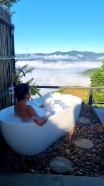 Tatil sırasında Chiang Rai Kuzey Tayland dağlarına bakan Asyalı kadınlar. Açık banyo, Doi Chang Dağı 'nda güneş doğarken sis ve sisle dolu küvet.
