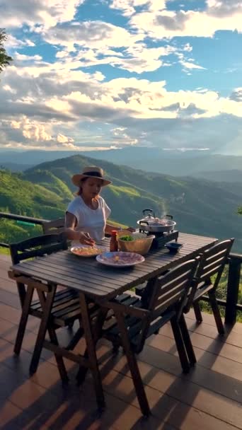 タイ北部での休暇中のアジア人女性 チェンライドイチャンの山のホームステイ小屋に滞在 日没時にタイのBbqで夕食を楽しんで — ストック動画