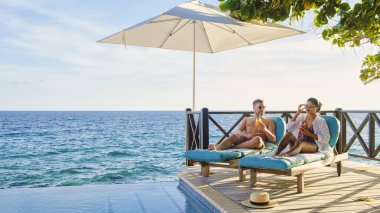 Curacao, tatilde yüzme havuzunda dinlenen bir çift orta yaşlı erkek ve kadın, Karayipler 'de tropik bir adada tatil yaparken Curacao' da havuz kenarında dinlenen erkekler ve kadınlar.