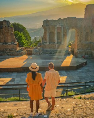 Taormina Sicilya, Taormina, Sicilya 'daki Antik Yunan Tiyatrosu' nun kalıntılarında gün batımını izleyen bir çift. Sicilya 'da tatilde olan iki erkek ve kadın.