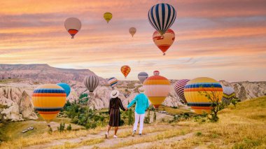 Kapadokya Türkiye 'de gün doğumunda Kapadokya' da sıcak hava balonlarıyla güneşin doğuşunu bekleyen Kapadokya Türkiye tepelerinde tatil yapan iki olgun erkek ve kadın.