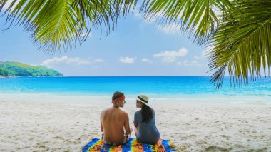 Anse Lazio Praslin Tropikal Seyşeller Adaları 'nda palmiye ağacının altında dinlenen çift. Seyşeller 'de lüks bir tatilde olan bir erkek ve kadın okyanusa bakıyor.