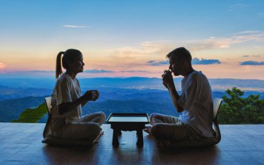 Kuzey Tayland 'da tatil için Japon usulü çay içen iki erkek ve kadın Chiang Rai Doi Chang dağlarındaki bir kulübede kalıyorlar.