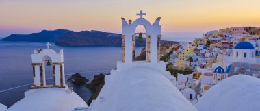 Günbatımında Santorini 'de geleneksel bir Yunan köyü olan Oia Santorini Yunanistan' ın okyanusu kenarındaki beyaz kiliseler ve mavi kubbeler. Oia Santorini gün batımında