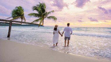 Koh Kood Adası Trat sahilinde gün batımını izleyen bir çift erkek ve kadın, palmiye ağaçları ve turkuaz renkli bir okyanus olan Ko Kut Adası 'nda tropik bir plaj.