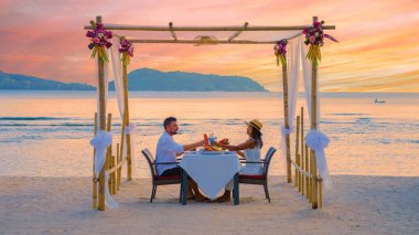Phuket Tayland 'da kumsalda romantik bir akşam yemeği, orta yaşlı bir çift ve Asyalı bir kadın ve Tayland sahilinde akşam yemeği yiyen Avrupalı bir adam lüks bir tatil sırasında.