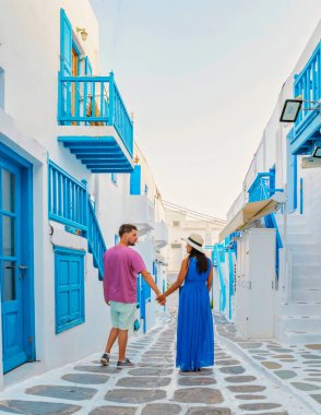 Mikonos köyünün renkli sokaklarında, Yunanistan 'ın Mykonos Yunan köyünün caddesinde romantik bir çift kadın ve erkek. Yunanistan 'da sabah tatilinde