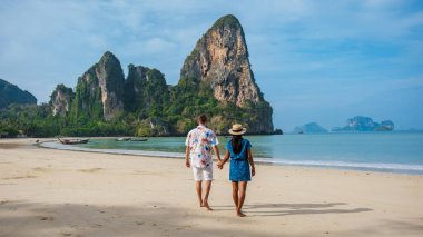 Railay Beach Krabi Tayland plajında yürüyen bir çift adam ve kadın, Railay Krabi 'nin tropikal plajı, çok ırklı bir çift kumsalda el ele yürüyorlar.