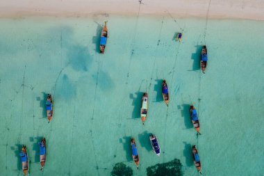 Koh Lipe Adası Güney Tayland Turkuaz renkli okyanusları ve Ko Lipe 'de beyaz kumlu plajları var. Kumsaldaki renkli uzun kuyruklu botlar İHA görüntüsünden görünüyor.