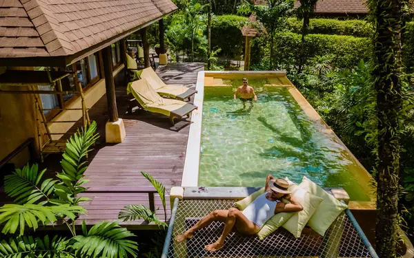スイミングプール付きモダンな家 ビーチのモダンなプールヴィラ タイの豪華なヴィラ プールヴィラのスイミングプールでリラックスしたタイの豪華な休暇で数人の男性と女性 — ストック写真