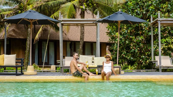 a couple of men and woman on a luxury vacation in Thailand relaxing in the swimming pool of a luxury resort on the beach of Koh Kood