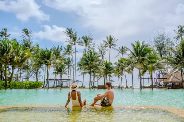 a couple of men and woman on a luxury vacation in Thailand relaxing in the swimming pool of a luxury resort on the beach of Koh Kood