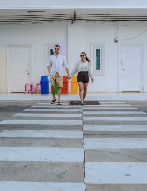 Pattaya Tayland 'da popüler bir kafeyi ziyaret eden bir çift kadın ve erkek bir kafe dışında bir bankta oturuyorlar.