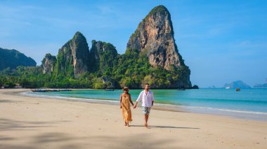 Railay Beach Krabi Tayland plajında yürüyen bir çift adam ve kadın, Railay Krabi 'nin tropikal bir plajı, çok ırklı bir çift kumsalda el ele yürüyorlar.