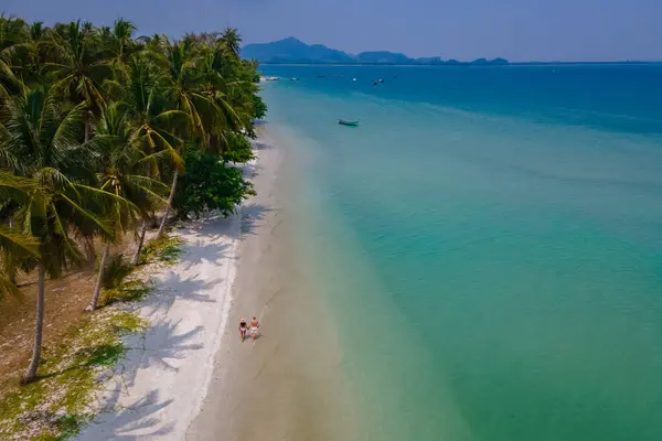 タイのアンダマン海にあるコ ムック熱帯の島で休暇中の男性と女性のカップルヤシの木とビーチを歩く男性と女性 — ストック写真