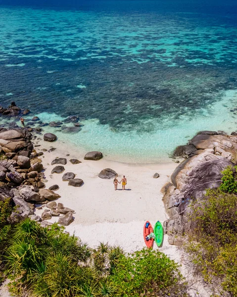 Koh Lipe Adası 'nın güneyindeki terk edilmiş bir plajda, turkuaz renkli okyanus ve Ko Lipe Adası sahilinde kayak yapan beyaz kumlu bir çift kadın ve erkek.