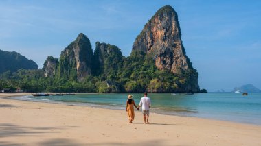 Railay Beach Krabi Tayland plajında yürüyen bir çift adam ve kadın, Railay Krabi 'nin tropikal plajı, çok ırklı bir çift kumsalda el ele yürüyorlar.