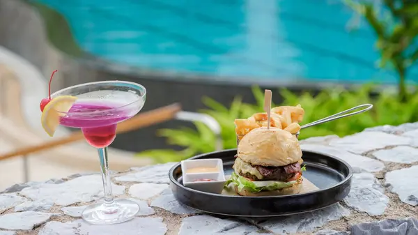 Hamburger and a cocktail at lunch at a restaurant looking out over the swimming pool, dinner in a restaurant by the pool in Pattaya Thailand