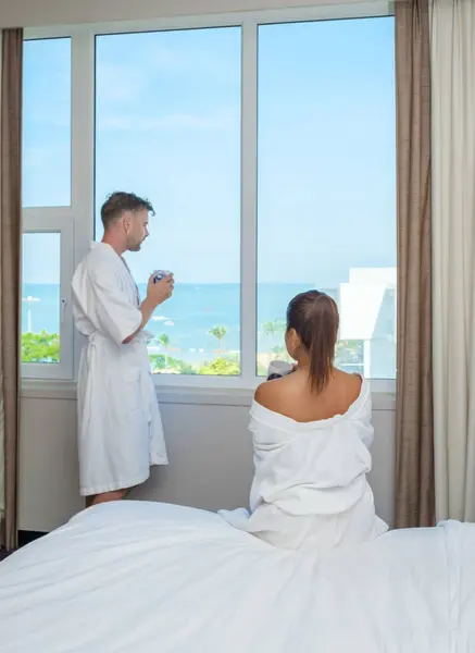 在泰国度过的一个豪华假期中 一对情侣正在度假 早上喝着咖啡 看着窗外的海滩和大海 — 图库照片