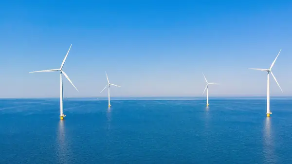 Windmill turbines offshore at sea with a blue sky, windmill turbines in the ocean of the Netherlands Europe