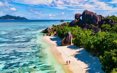 Anse Source d 'Argent, La Digue Seychelles, tropik bir tatil sırasında tropikal bir plajda yaşayan birkaç beyaz erkek ve Asyalı kadın, La Digue Seychelles