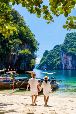 Tayland 'daki Koh Hong Adaları' nın Koh Loa Lading Krabi Tayland plajındaki erkekler ve kadınlar. Kireçtaşı kayalıkları ve uzun kuyruklu tekneleri olan güzel bir sahil.