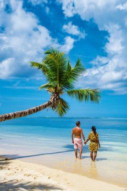 Anse Royale plajı, tatilde olan bir çift erkek ve kadın sahilde yürüyen Seyşeller, palmiye ağaçları ve Mahe Seyşeller 'de mavi bir okyanusu olan Mahe Seyşeller tropik plajı.. 