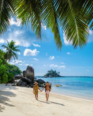 Anse Royale plajı, Seyşeller 'de tatilde olan birkaç erkek ve kadın, palmiye ağaçları ve mavi okyanuslu Mahe Seyşelles tropikal plajı.