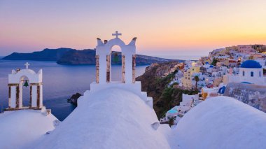 Beyaz kiliseler, yaz boyunca Santorini 'de geleneksel bir Yunan köyü olan gün batımında Oia Santorini Yunanistan' ın okyanusu kıyısında mavi bir kubbe.