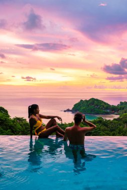Genç bir çift, tropik bir adada tatil yaparken yüzme havuzunda. Gün batımında sonsuz havuzda bir kadın ve bir erkek. Tayland 'da lüks bir havuz villasında lüks bir tatil.