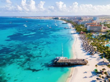 Palm Beach Aruba Karayipleri, güneşli bir günde Aruba Antilleri 'nde palmiye ağaçları olan uzun kumlu plaj.