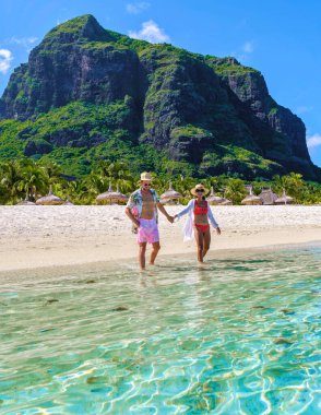 Mauritius 'ta tropikal bir plajda erkek ve kadın, Mauritius Le Morne Plajı' nda balayı tatilinde olan bir çift, arkasında Le Morne Dağı olan bir çift.