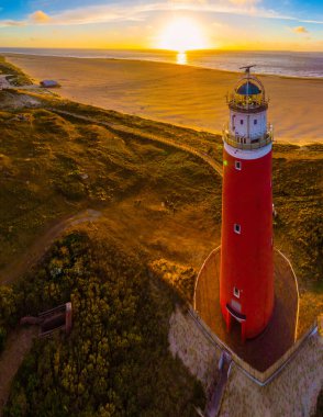 Texell deniz feneri gün batımında Hollanda 'da yazın Dutch Island Texel' de Wadden Adası 'nda kum tepeleri vardı. Kumsalın yukarısından deniz feneriyle drone hava görüntüsü