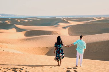 Maspalomas sahilinde yürüyen çift, İspanya Gran Kanaryası 'nda, Maspalomas İspanya' nın kum tepeleri çöllerindeki erkekler ve kadınlar Avrupa 'da tatilde.