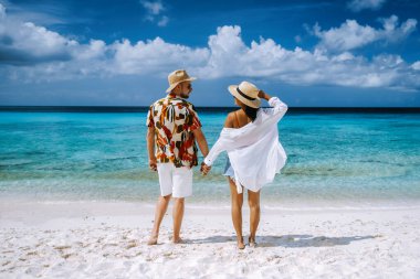 Playa Porto Marie plajı Curacao, okyanus Karayip denizinde turkuaz suyu olan beyaz tropikal bir sahil, Curacao 'da tatilde olan birkaç erkek ve kadın.