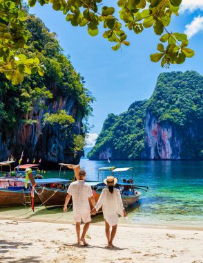 Tayland 'daki Koh Hong Adaları' nın bir parçası olan Koh Loa Lading Krabi Tayland 'ın Tropikal lagünündeki kadın ve erkekler. Güneşli bir günde kireçtaşı kayalıkları ve uzun kuyruklu tekneleri olan güzel bir sahil.