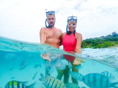 A couple of men and a woman on a snorkeling trip at Samaesan Thailand. dive underwater with Nemo fishes in the coral reef sea pool. couple swim activity on a summer beach holiday  clipart