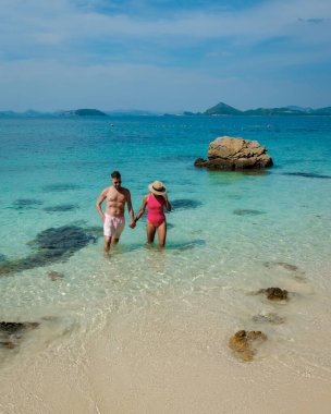 Bir çift Avrupalı erkek ve Asyalı kadın Ko Kham Adası Sattahip Chonburi Samaesan Tayland 'a tekne gezisine gittiler. Tropik bir adada turkuvaz renkli bir çift plajda dinleniyorlar.